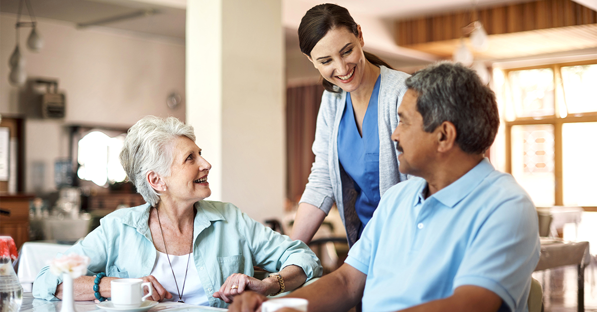 Two seniors chatting with caring staff member